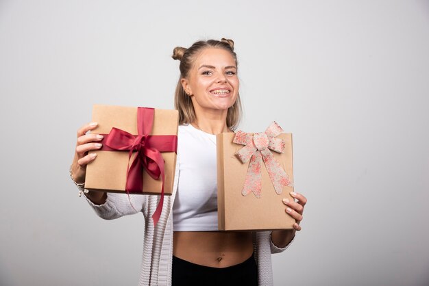 Mujer sonriente mostrando regalos navideños con expresión feliz.
