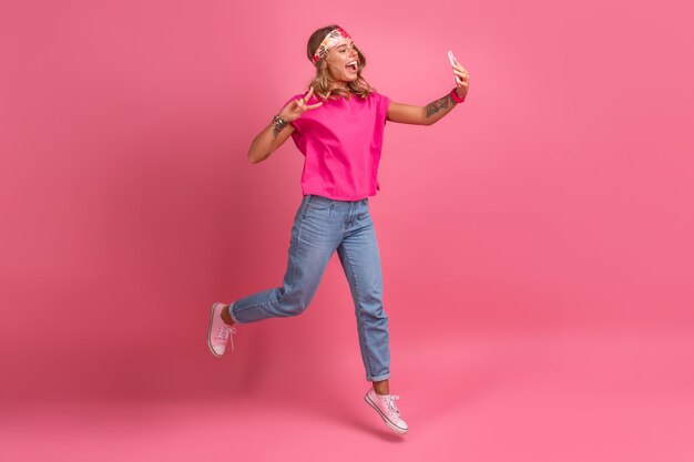 Mujer sonriente muy linda en accesorios de estilo hippie boho camisa rosa sonriendo diversión emocional posando en rosa