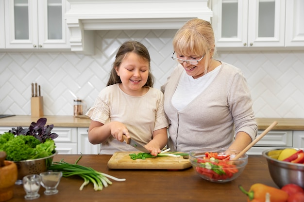 Foto gratuita mujer sonriente y niña cocinando tiro medio