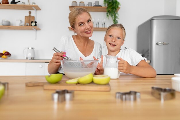 Mujer sonriente y niño cocina tiro medio