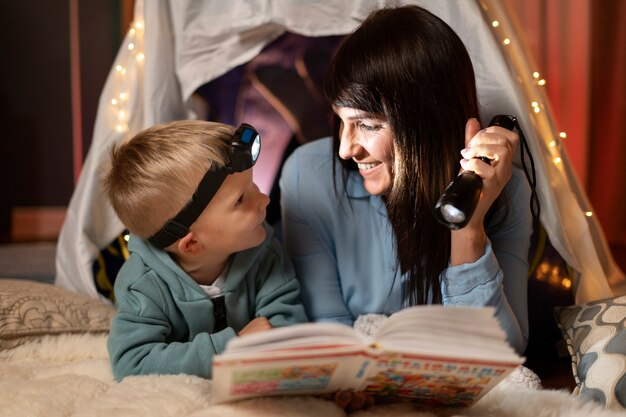Mujer sonriente y niño leyendo plano medio