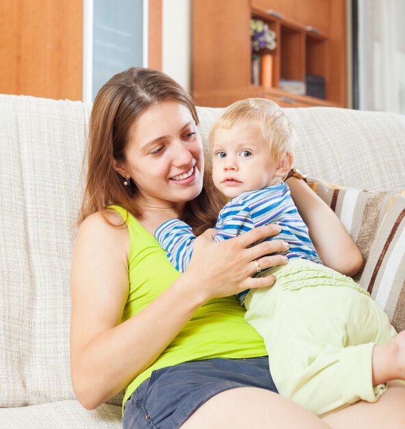 mujer sonriente con el niño en el sofá