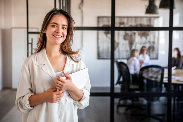 Mujer sonriente en la oficina trabajando en tableta