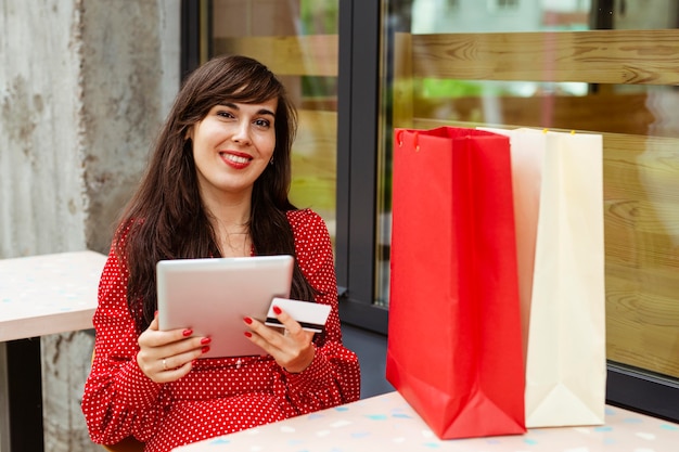 Mujer sonriente ordenar artículos a la venta con tableta y tarjeta de crédito