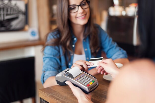 Mujer sonriente pagando café con tarjeta de crédito