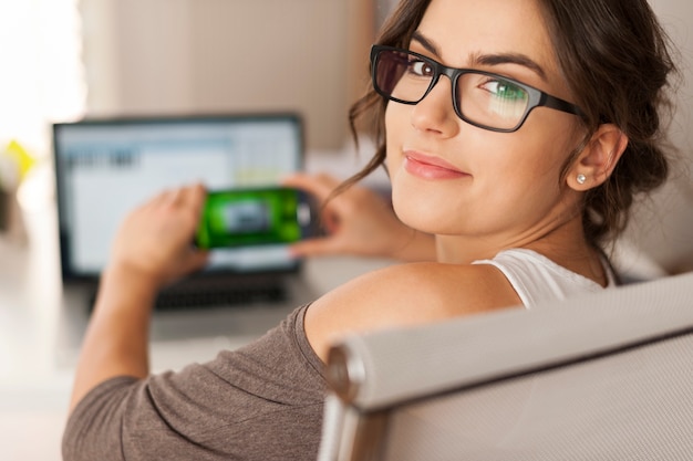 Mujer sonriente pagando facturas escaneando el código qr