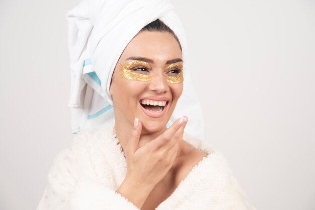 Mujer sonriente con parches debajo de los ojos en bata de baño