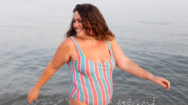 Mujer sonriente pasando un buen rato en la playa en el agua