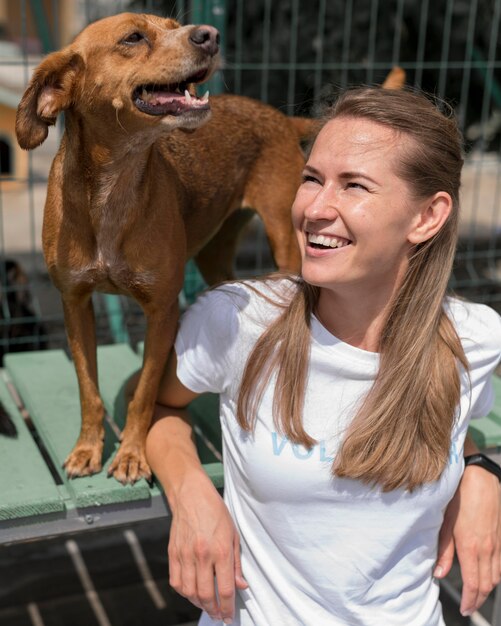 Mujer sonriente pasar tiempo con lindo perro de rescate en el refugio