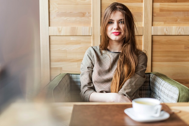 Mujer sonriente con el pelo largo en una cafetería