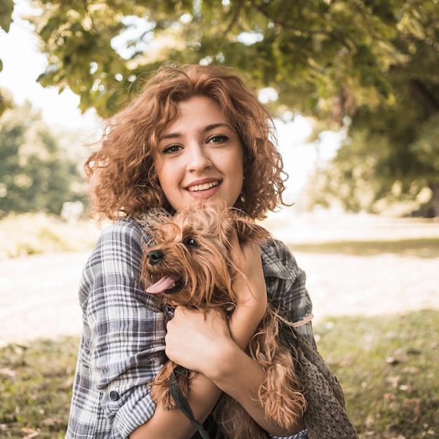 Mujer sonriente con perro en el parque