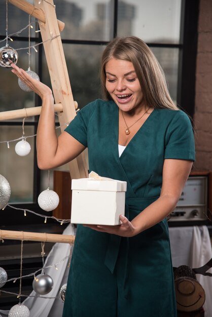 Mujer sonriente de pie con un regalo de Navidad en casa