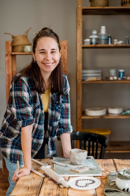 Foto gratuita mujer sonriente de pie en su taller de cerámica