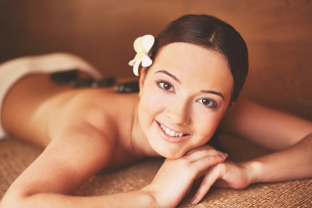 Mujer sonriente con piedras calientes en el spa