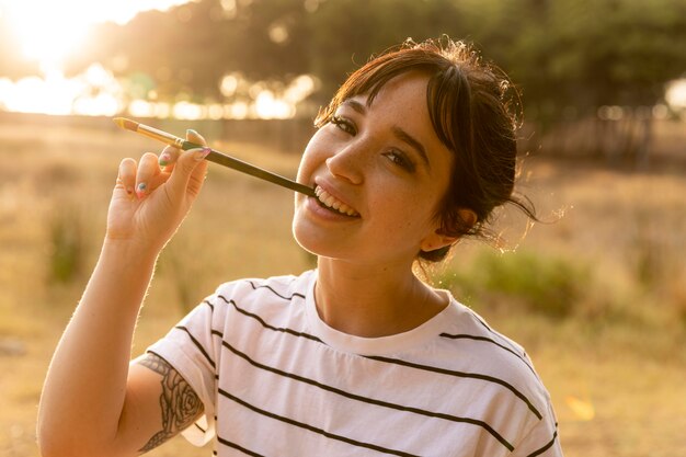 Mujer sonriente con pincel en la boca