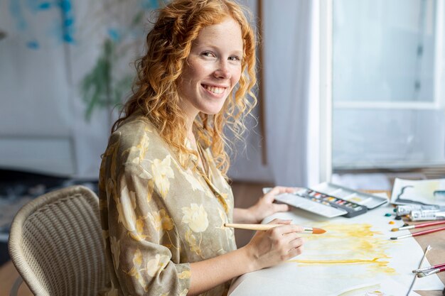 Mujer sonriente pintando en interiores