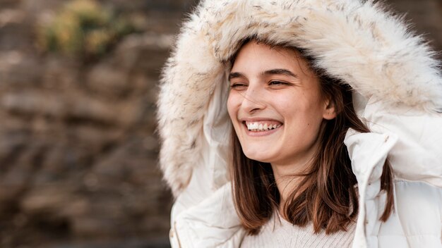 Mujer sonriente en la playa con chaqueta de invierno y espacio de copia