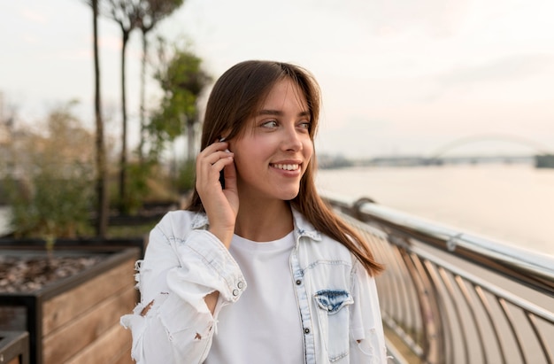 Mujer sonriente poniéndose auriculares mientras está al aire libre
