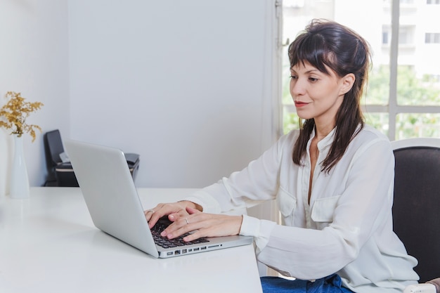 Mujer sonriente con portátil en el escritorio