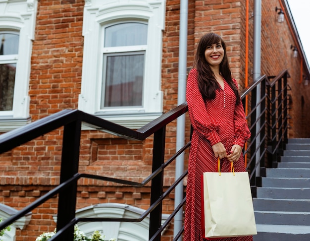 Foto gratuita mujer sonriente posando al aire libre con bolsas de la compra.