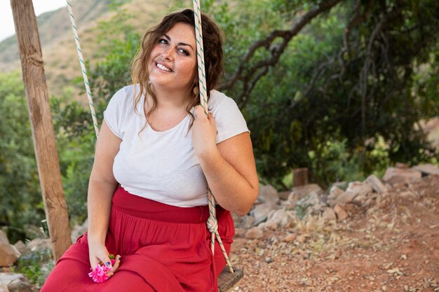 Mujer sonriente posando al aire libre en columpio