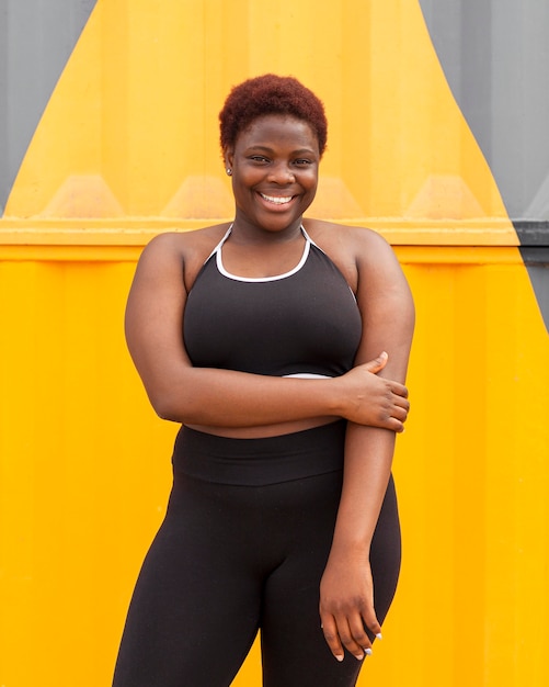 Mujer sonriente posando al aire libre en ropa deportiva