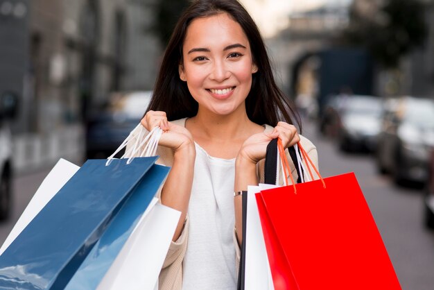 Mujer sonriente posando con bolsas de la compra después de la compra de venta