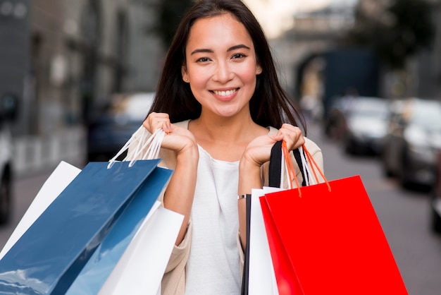 Mujer sonriente posando con bolsas de la compra después de la compra de venta