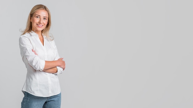 Mujer sonriente posando con los brazos cruzados y copie el espacio