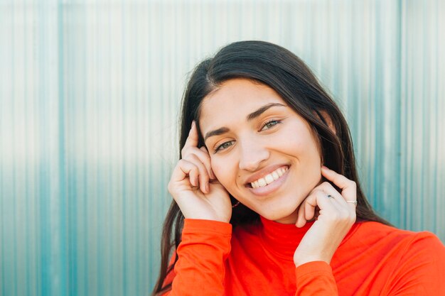 mujer sonriente posando contra la pared corrugada