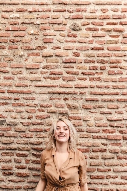 Mujer sonriente posando contra la pared de ladrillo con espacio de copia