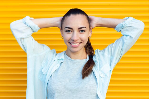 Mujer sonriente posando con fondo amarillo