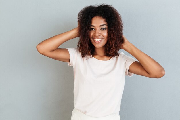 Mujer sonriente posando y jugando con su cabello mientras está de pie