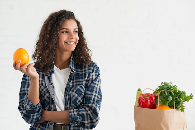 Mujer sonriente posando junto a una bolsa de verduras