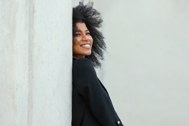 Foto gratuita mujer sonriente posando junto a la pared de tiro medio