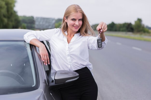 Mujer sonriente posando con las llaves del auto