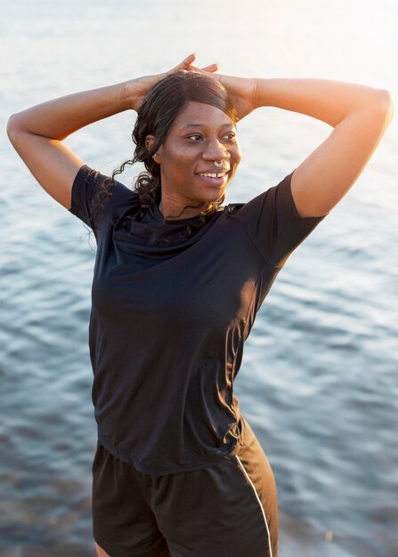 Mujer sonriente posando mientras se ejercita junto al lago