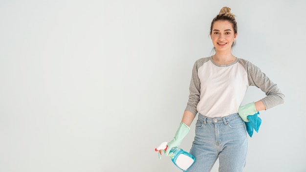 Mujer sonriente posando mientras sostiene el paño y la solución de limpieza