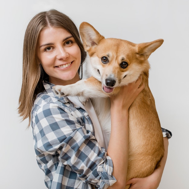 Mujer sonriente posando mientras sostiene a su adorable perro