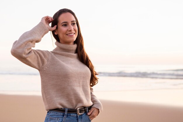 Mujer sonriente posando en la playa al atardecer