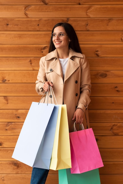 Mujer sonriente posando sosteniendo bolsas de la compra.