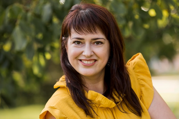 Mujer sonriente posando con un vestido amarillo al aire libre