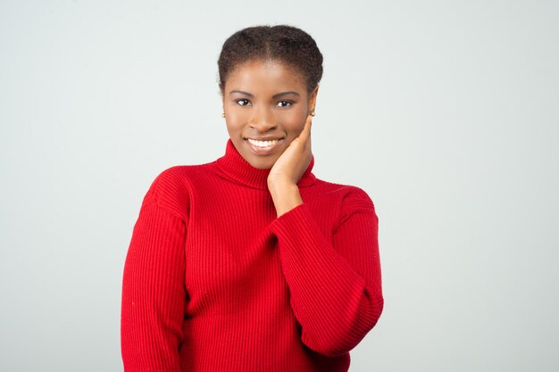 Mujer sonriente positiva que toca la piel de la cara