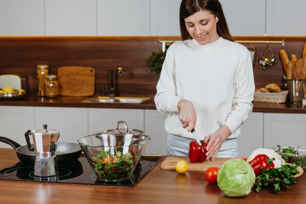 Mujer sonriente preparando comida en la cocina de casa