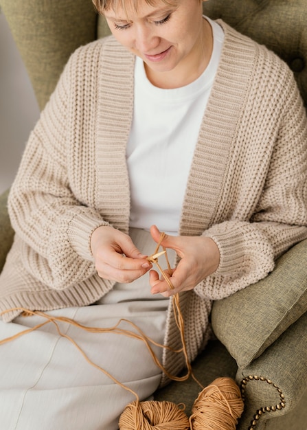 Mujer sonriente de primer plano en el sillón de tejer