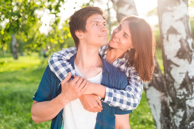 Mujer sonriente que abraza al hombre en bosque