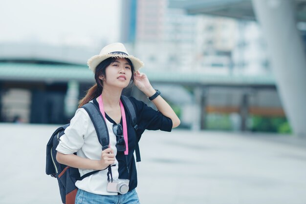 Mujer sonriente que camina al aire libre, señora joven que admira vista de la ciudad con la calzada y edificios en fondo.