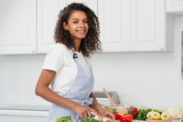 Mujer sonriente que cocina y que mira al fotógrafo