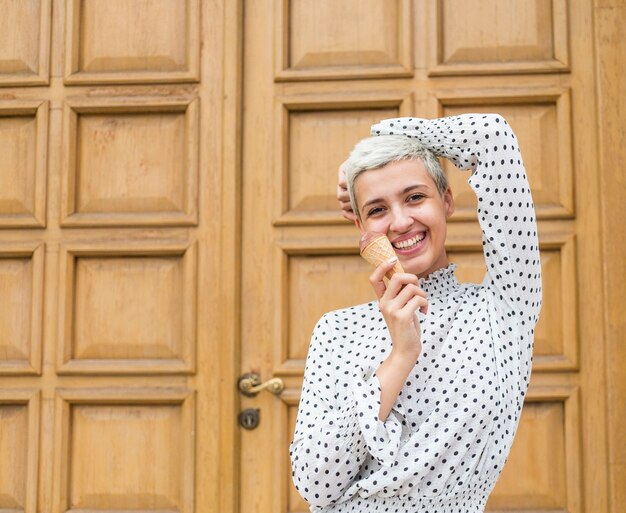 Mujer sonriente que come el helado