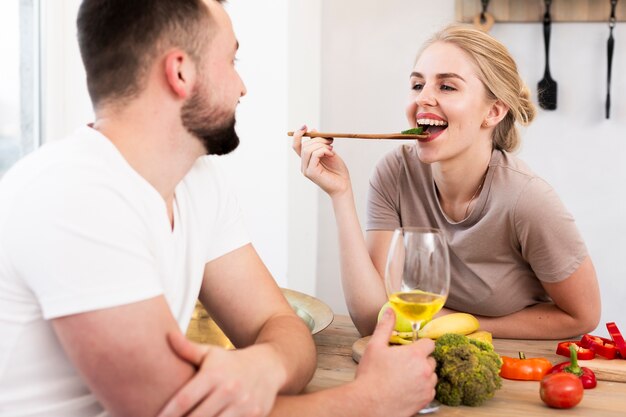 Mujer sonriente que come con su hombre